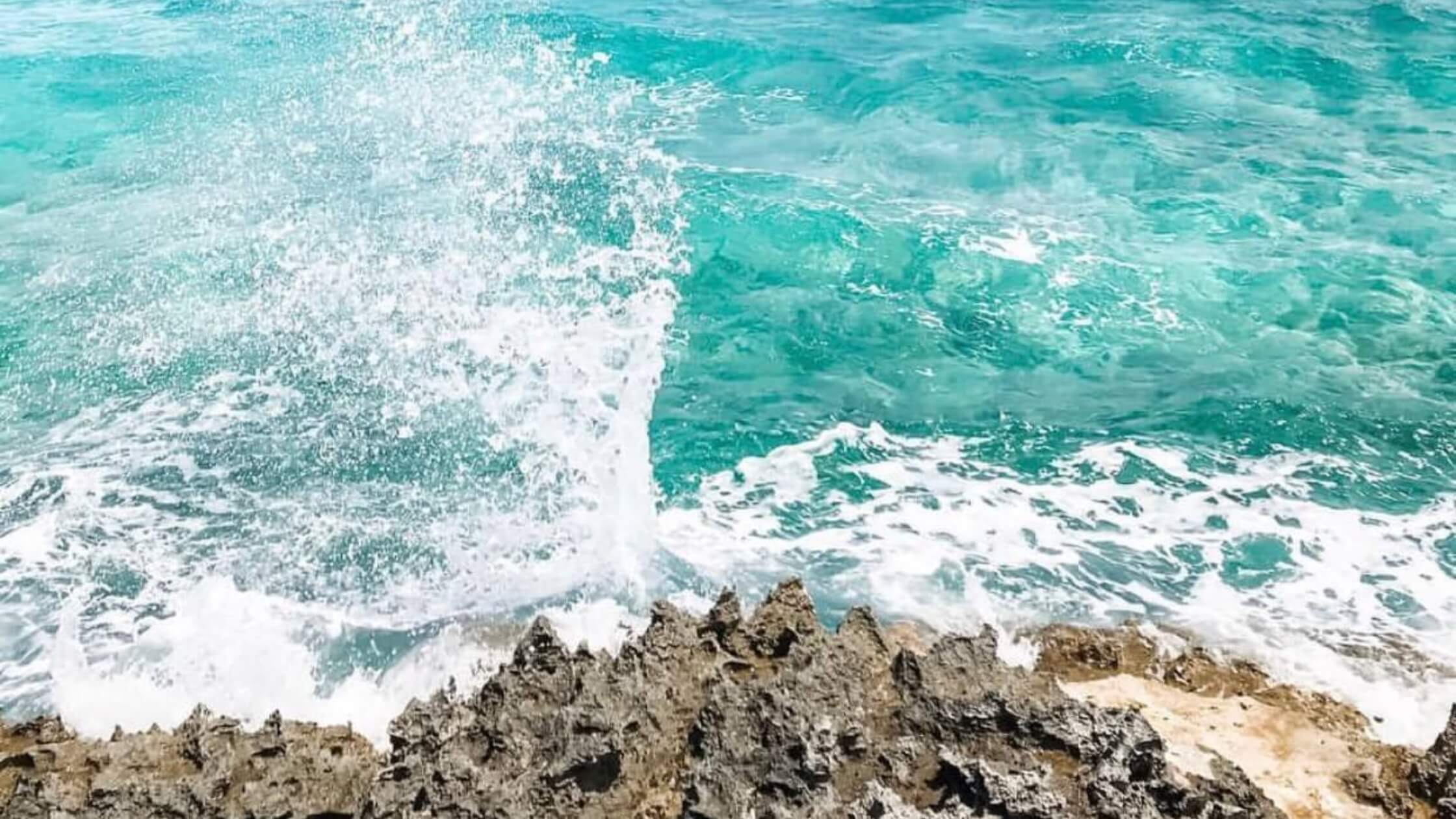 Waves crashing into rocks on the beach of Sandals Royal Bahamian Resort.