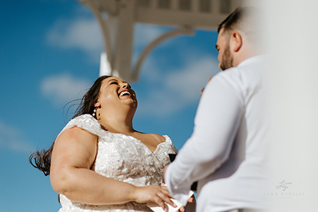 Bride laughing while getting married in a gazebo on a beach in Mexico