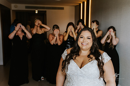 Bridesmaids hiding their eyes from seeing the bride in her wedding gown