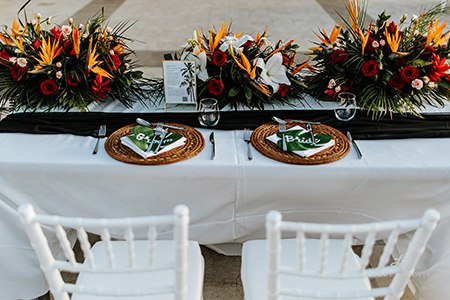 sweetheart table showing the place settings for the bride and groom including tropical florals