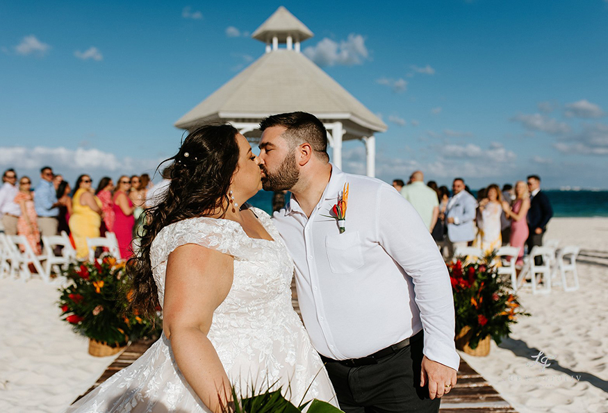 Couple kissing on beach in front of a gazebo at destination wedding in Mexico