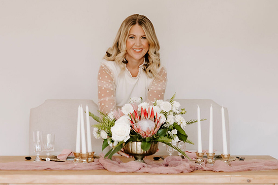 Dana setting a protea floral arrangement onto a table at a destination wedding.