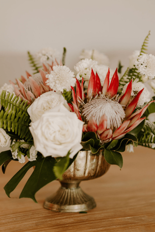 floral arrangement with protea in a short gold vase for a trending 2024 destination wedding