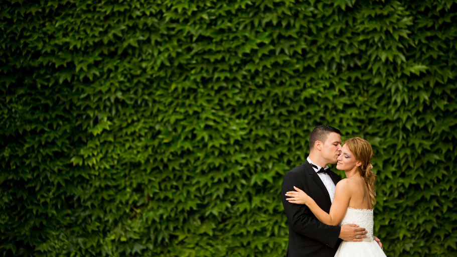 Unconventional Wedding Decor: bride and groom standing in front of a statement floral wall