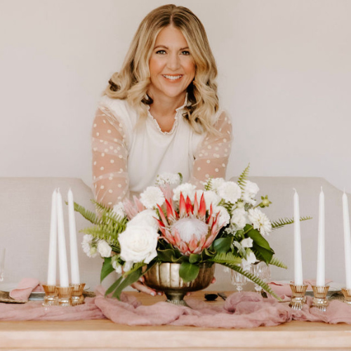 woman placing a floral bouquet onto a table at a wedding reception