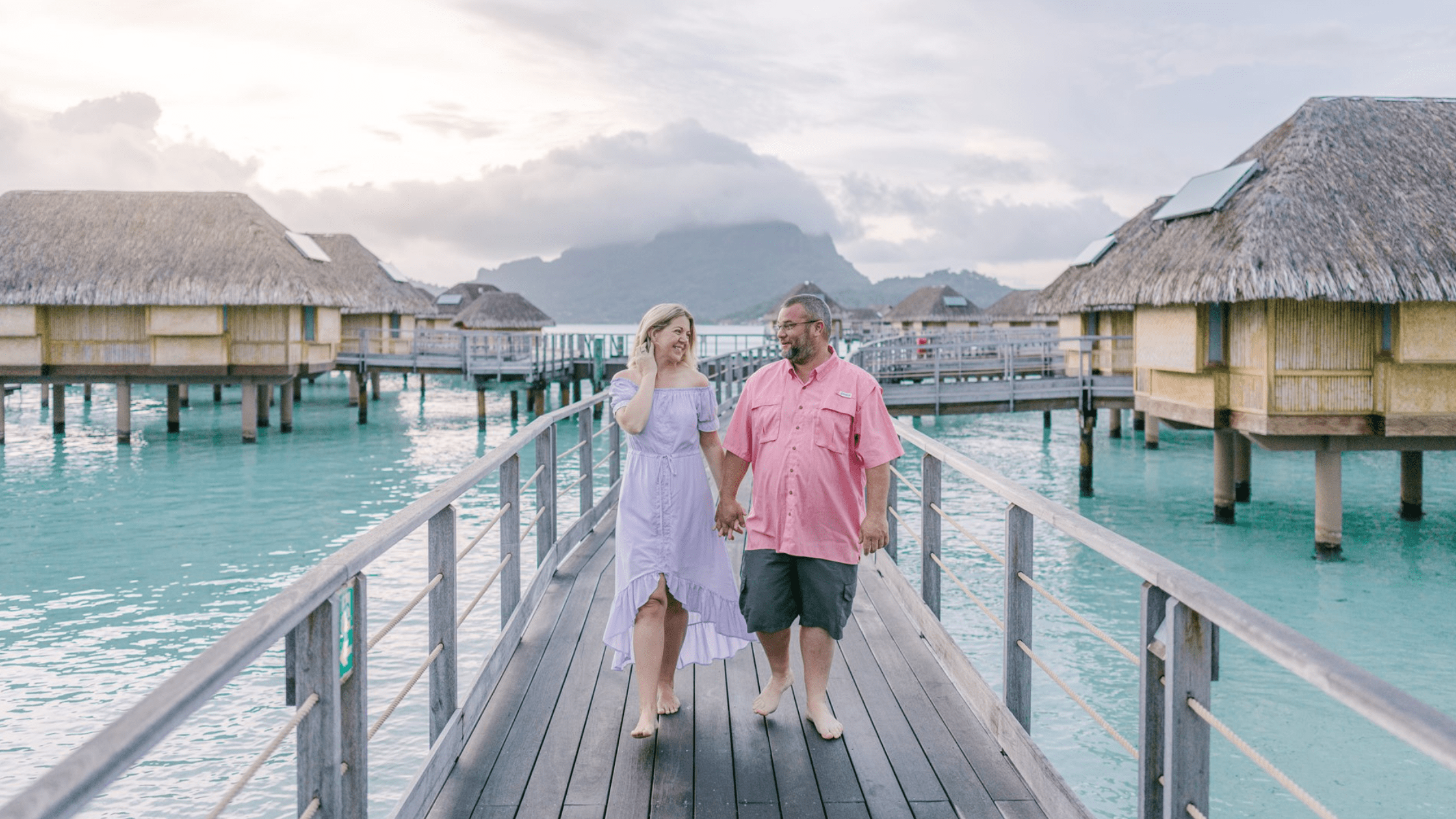 couple walking hand in hand on dock of overwater bungalow in Bora Bora