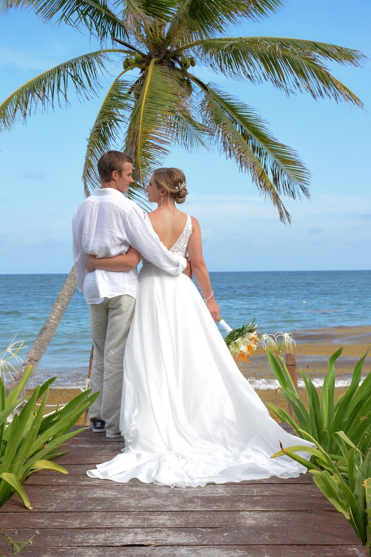 couple getting married on the beach near a palm tree and water