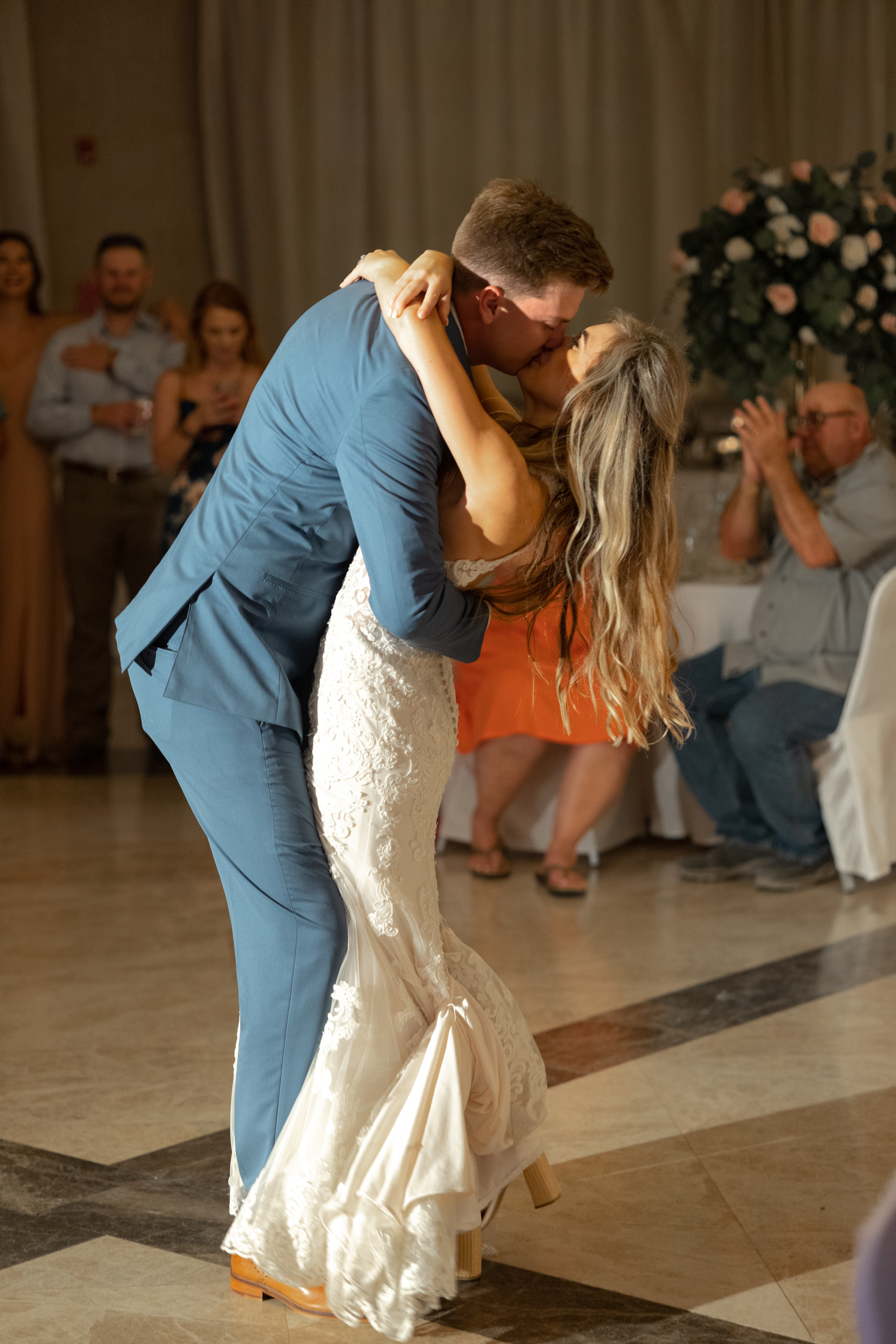 Bride and groom kiss on the dance floor, surrounded by their happy destination wedding guests celebrating the special moment.