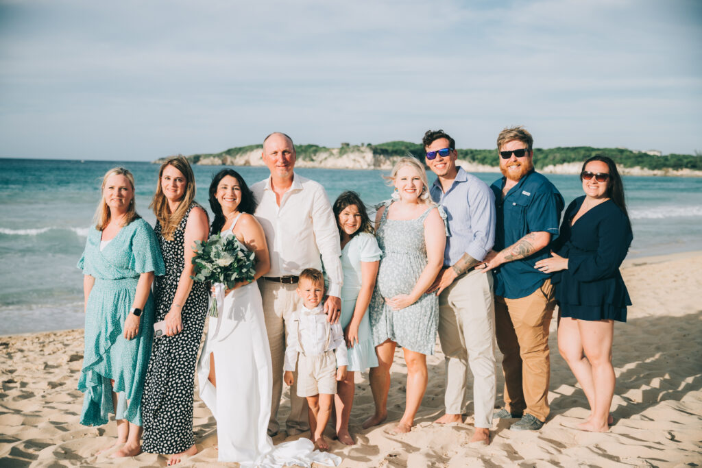 Family and friends gather on the beach with the bride and groom, capturing the joy of the day with destination wedding guest.