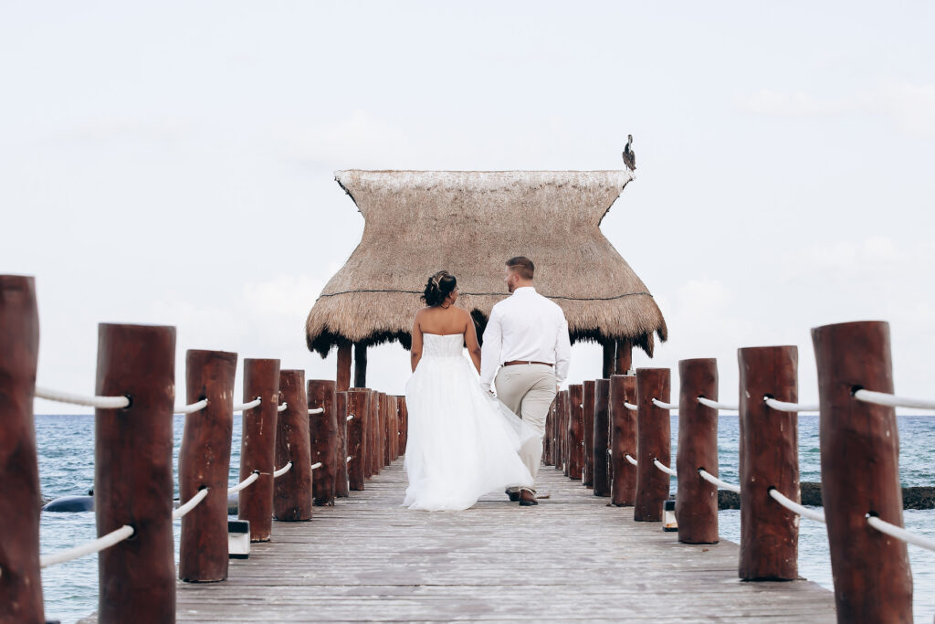 Couple walking hand-in-hand on a scenic pier—illustrating the dream outcome when destination wedding red flags are handled early.