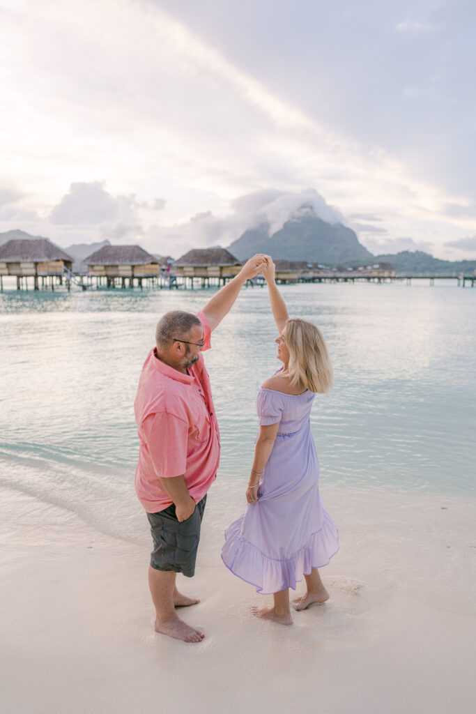 Couple dancing on the beaches of Bora Bora with the iconic turquoise waters and overwater bungalows.