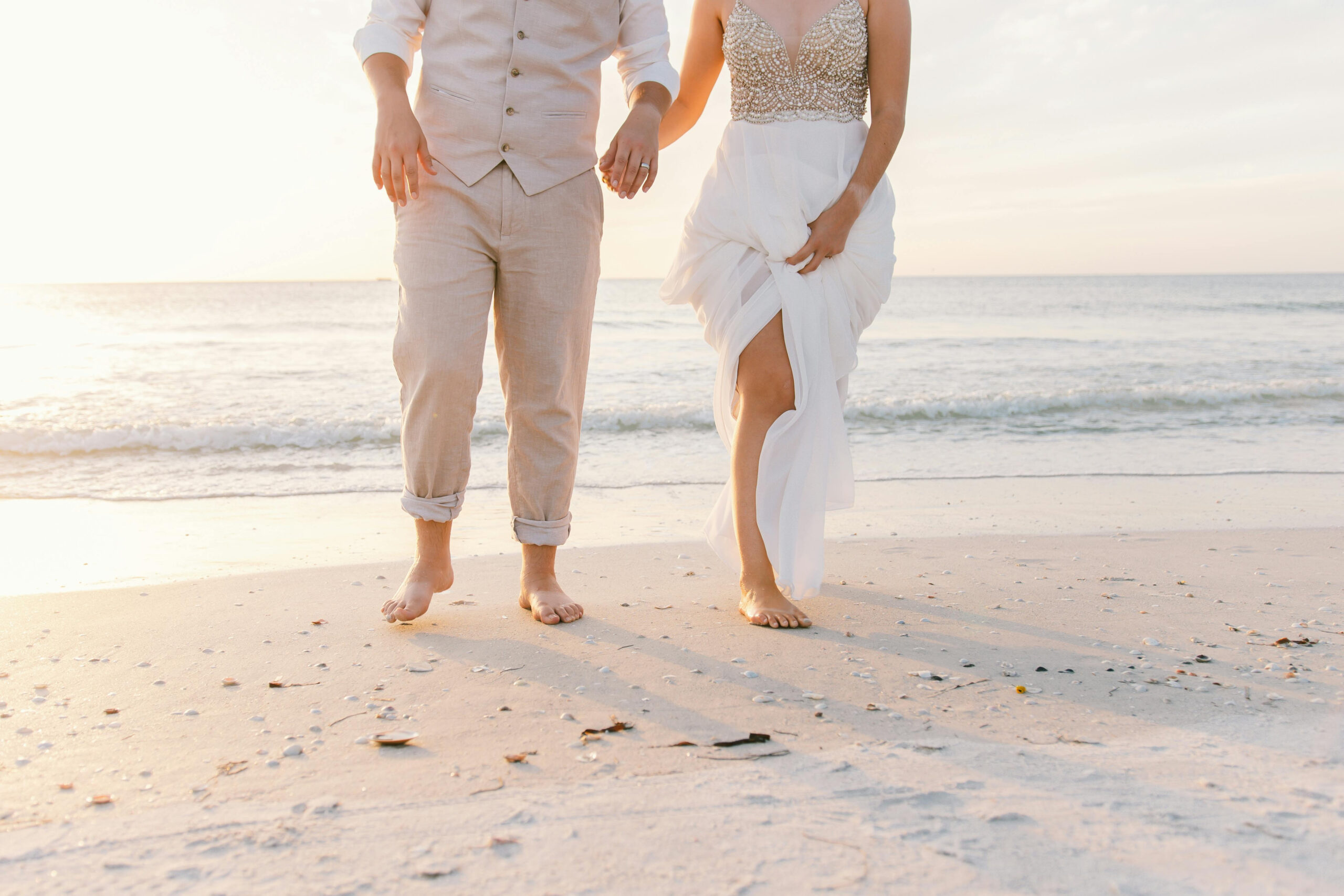 destination wedding website, couple walking barefoot in the sand