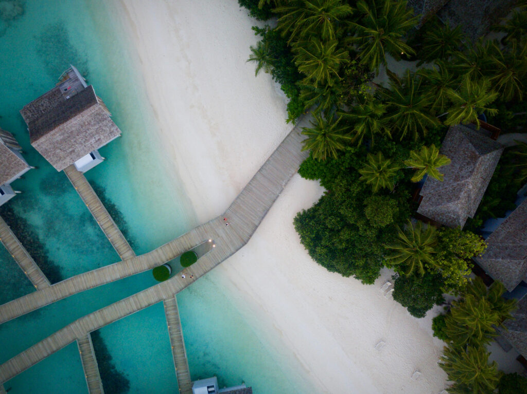 Overwater villas and tropical beach resort viewed from above, perfect for a luxury honeymoon itinerary.