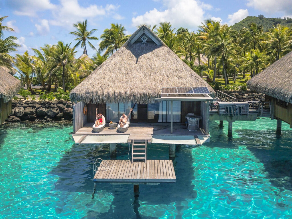Couple relaxing at an overwater villa in the South Pacific, enjoying one of the most peaceful luxury honeymoon destinations.