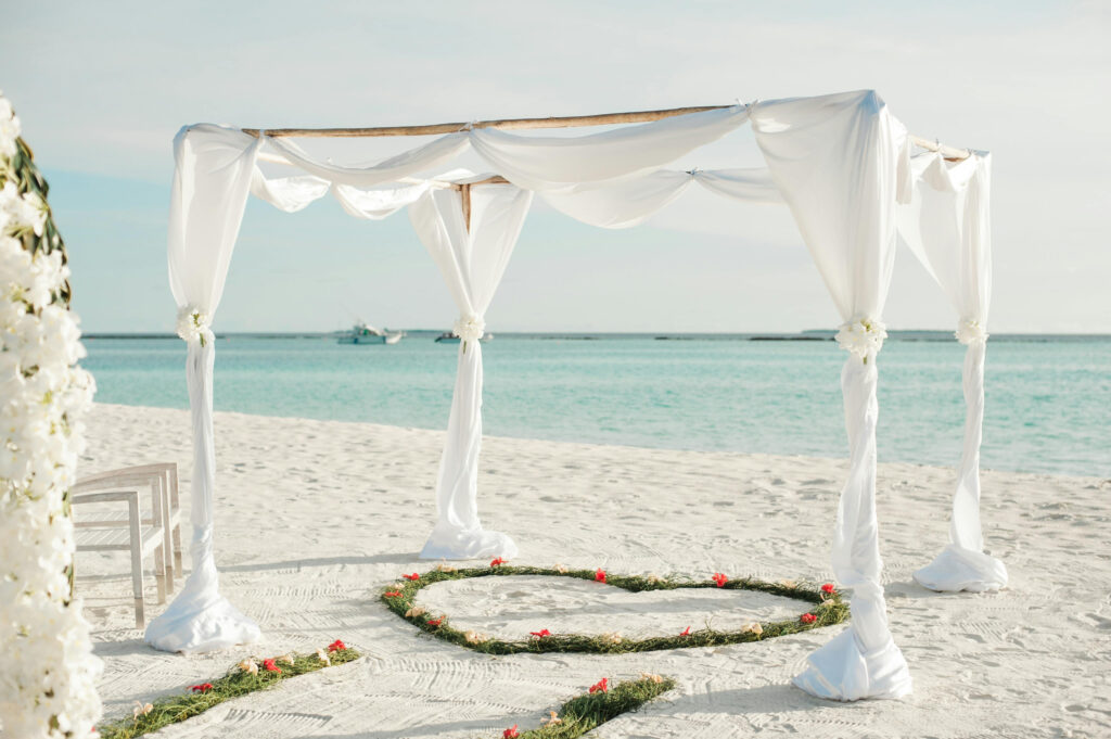 Romantic beach ceremony setup with white draping, featured in destination wedding quiz planning guide.