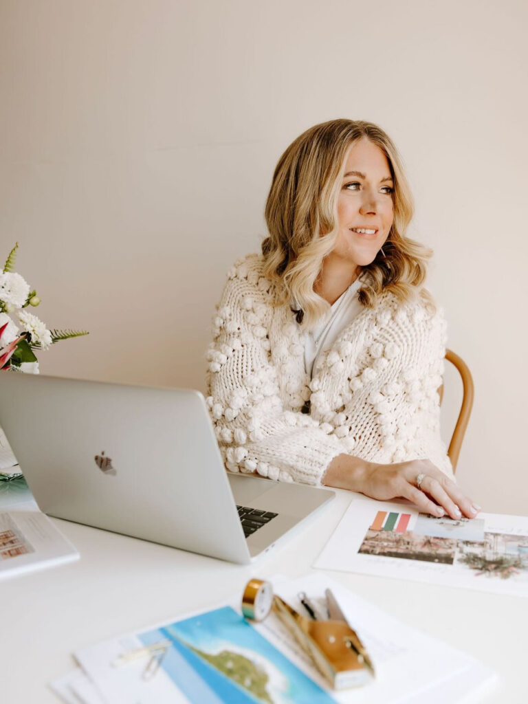  Woman smiling at laptop while planning a destination wedding, featured in a wedding quiz blog.