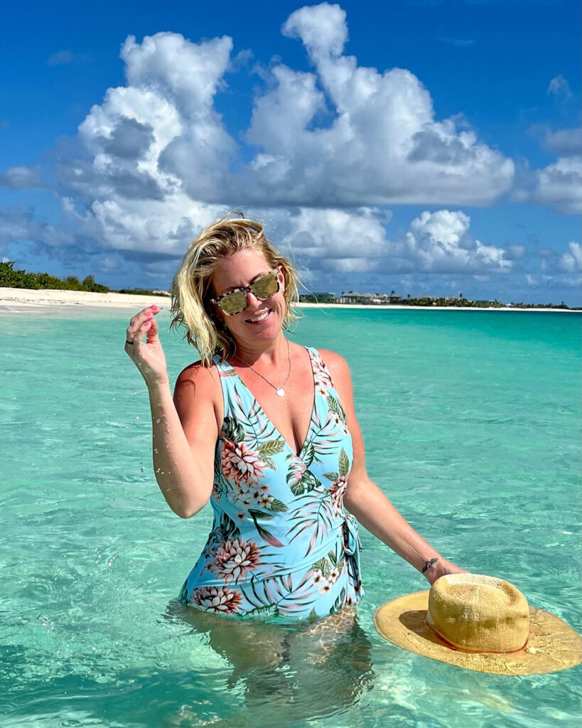 Smiling woman in tropical swimsuit enjoying turquoise ocean, perfect backdrop for a Destination Wedding Planner’s travels.