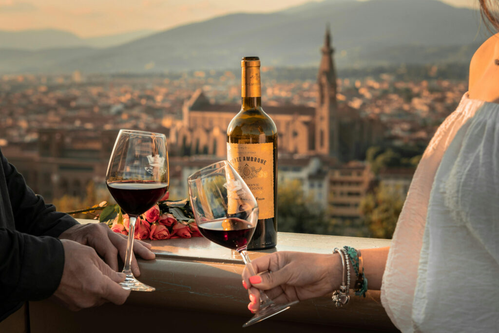 Couple toasting red wine at sunset with city view, enjoying romantic honeymoon upgrades and unforgettable moments.