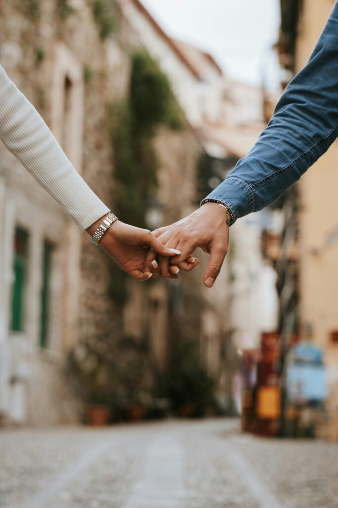 Couple holding hands while walking through a charming street, symbolizing romance and honeymoon upgrades experience.