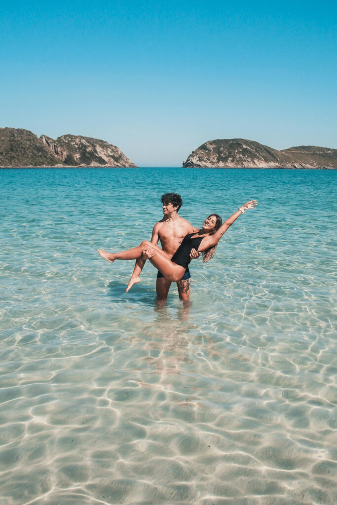 Couple enjoying crystal-clear ocean, playful and romantic moment showing the joy of honeymoon upgrades in paradise.