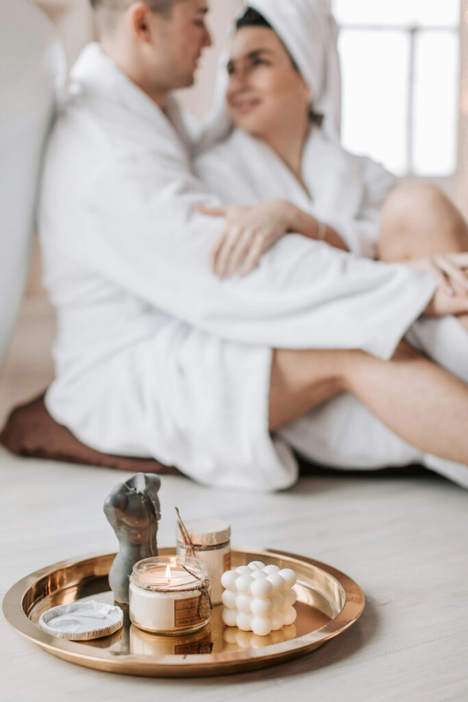Couple in robes enjoying a peaceful wedding retreat with candles and spa essentials on a tray.