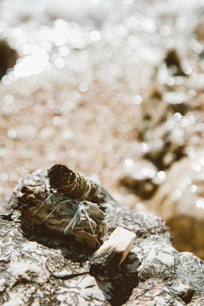 Bundles of sage and palo santo resting on a rock, prepared for a spiritual cleansing ritual.
