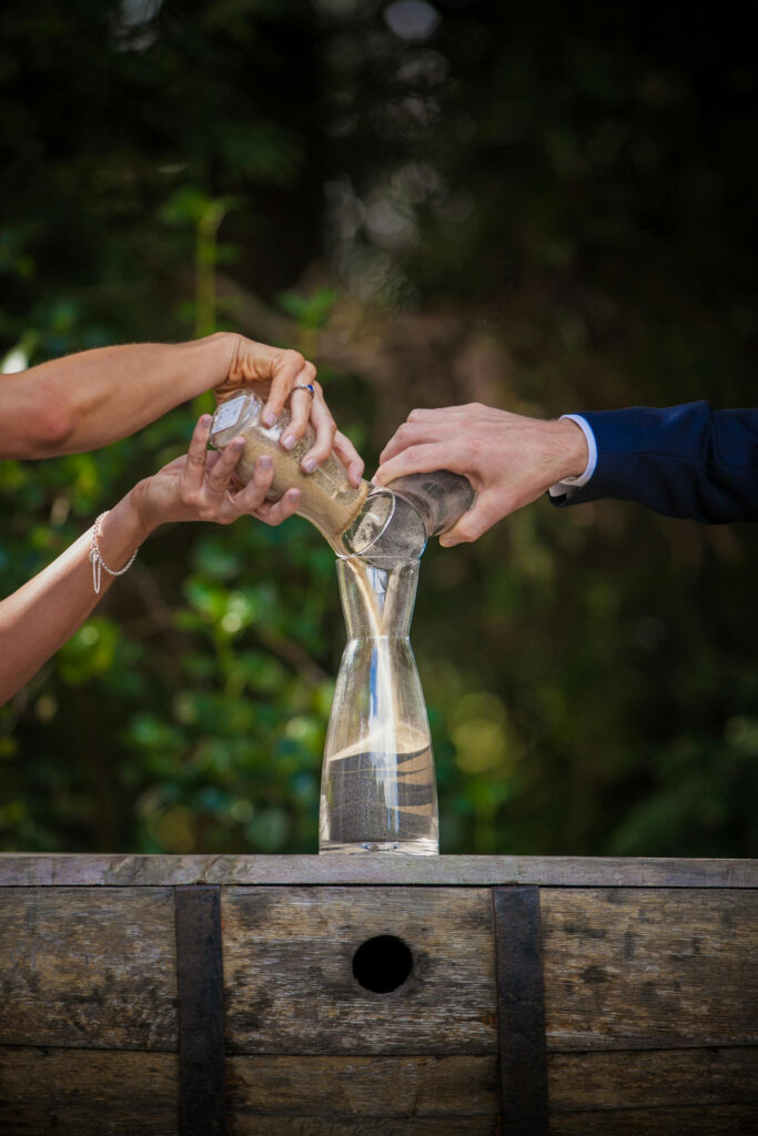 Bride and groom pour sand into a shared vessel during a unity sand ceremony at their wedding.