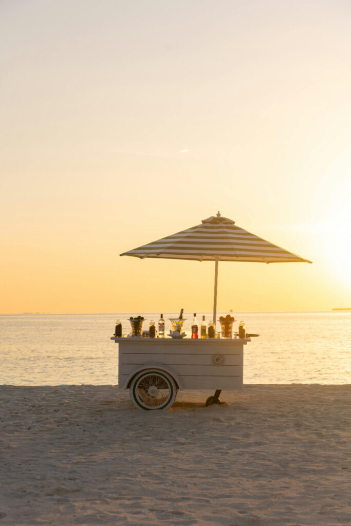 Charming beachside bar cart at golden hour—perfect for casual, stylish beachfront welcome events by the water.