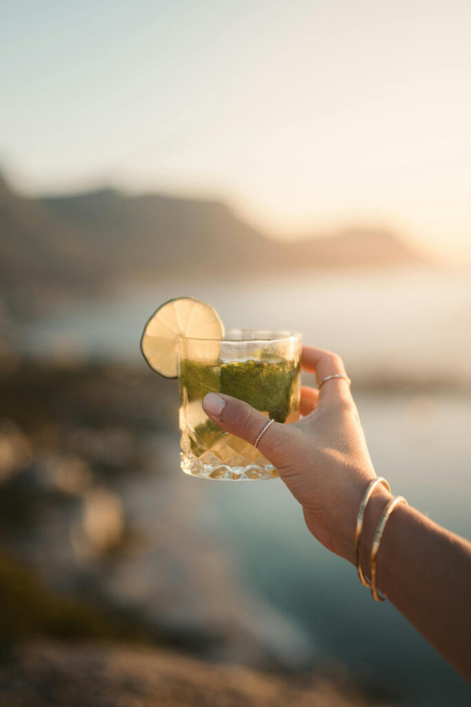 Hand holding a lime cocktail at sunset—an ideal detail for beachfront welcome events with coastal views.