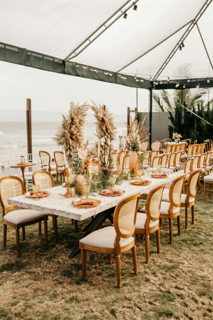 Boho-chic beachside tablescape with pampas grass, perfect for elegant beachfront welcome events with ocean views.