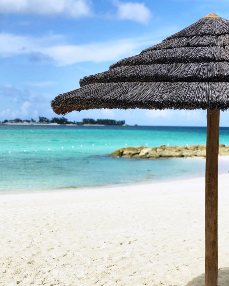 Thatched beach umbrella on a tropical shore, perfect setting for a mid-week destination wedding retreat.