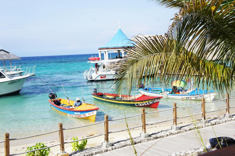 Colorful boats float in turquoise Caribbean water, creating a vibrant backdrop for a perfect destination wedding spot.