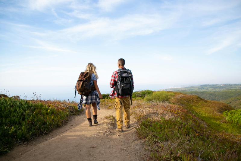 Couple hiking along a scenic coastal trail, perfect for adventurous travelers choosing where to honeymoon.