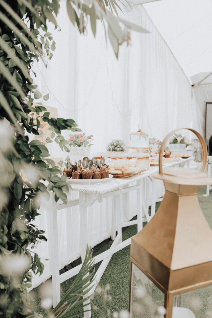 Elegant dessert table setup at a reception for guests attending a destination wedding, featuring floral accents, sweet treats, and soft white decor.