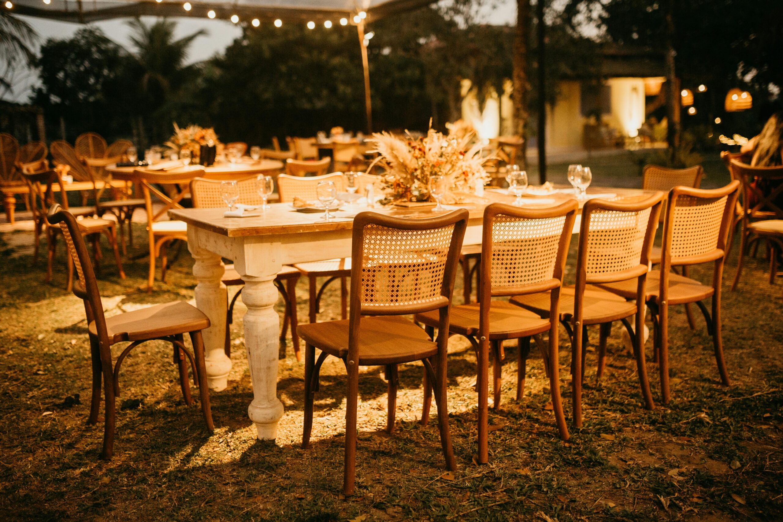 Outdoor reception setup for guests attending a destination wedding, featuring wooden chairs and rustic floral decor.