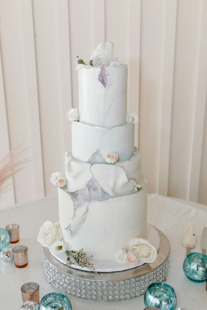 Elegant three tier wedding cake with soft pastel details and delicate florals.