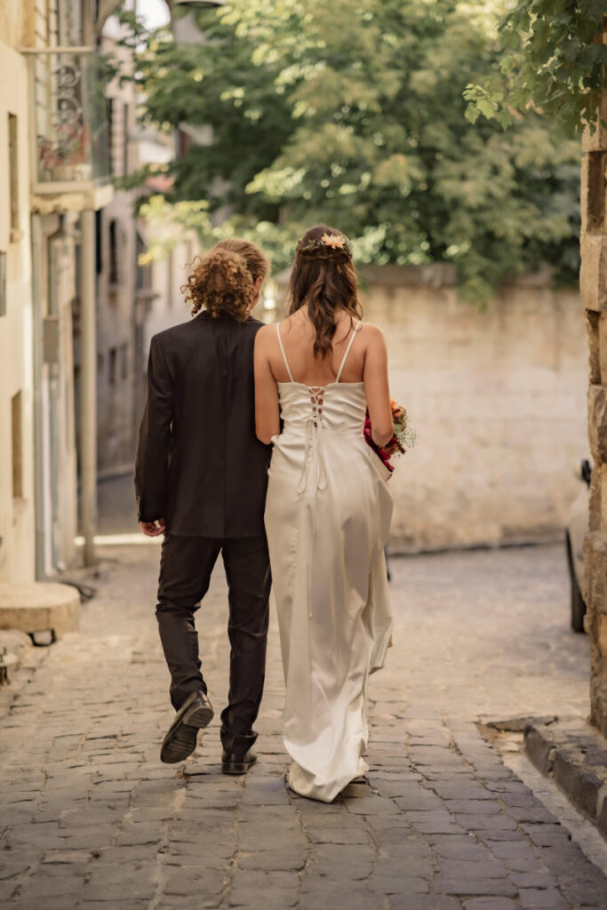 Bride and groom walking down a cobblestone street in a romantic historic town setting
