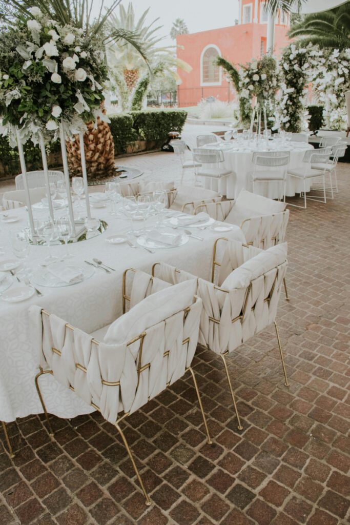 Elegant outdoor reception setup with white tables and woven chairs, perfect for destination wedding ideas in a courtyard setting