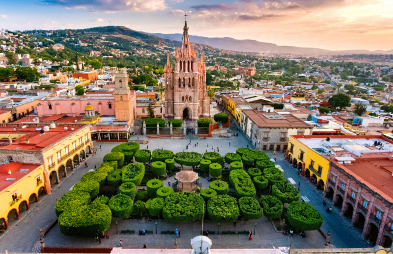 Colorful city square with pink cathedral and manicured gardens at sunset in a historic Mexican town