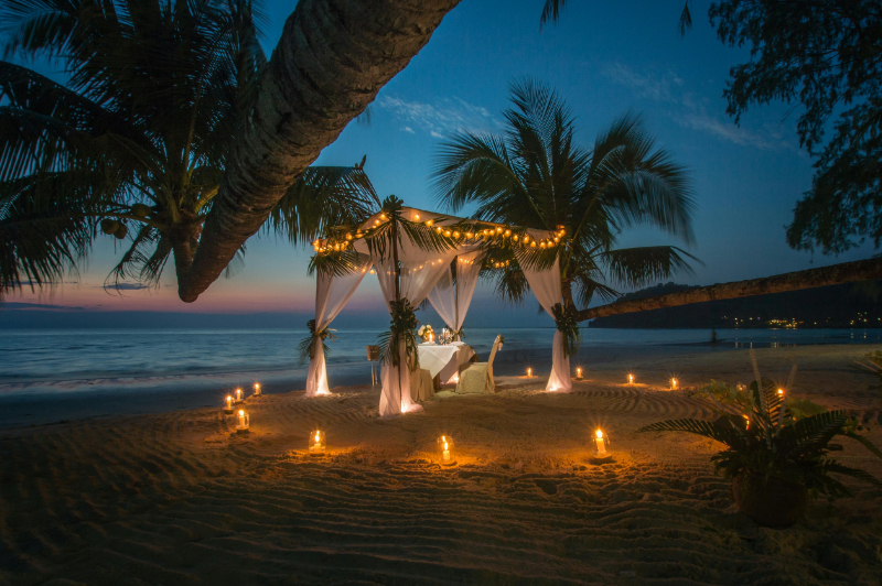 Romantic candlelit beach dinner setup during luxury honeymoon in Mexico at sunset.