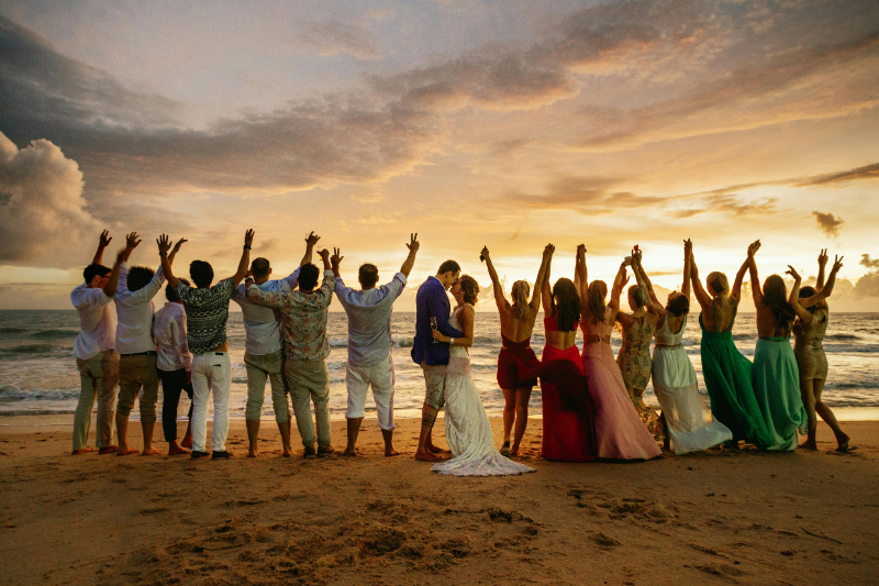Joyful wedding guests celebrating on a beach at sunset, capturing the best wedding ever atmosphere