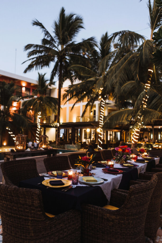 Elegant outdoor resort dinner setup with candlelight, floral centerpieces, and tropical evening ambiance by the pool