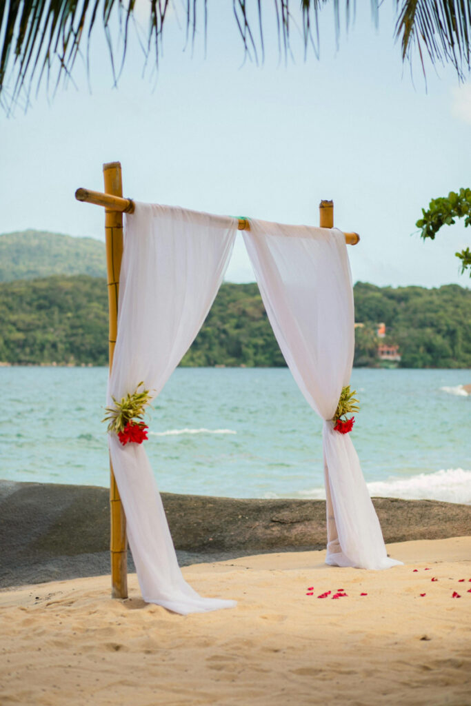 Simple beach wedding ceremony setup with white drapery and ocean view, calm and elegant setting
