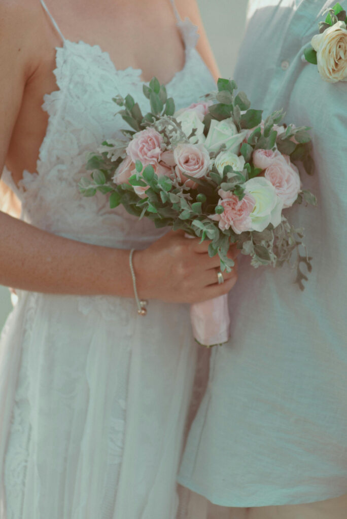 Bride holding blush and white bouquet with greenery, romantic detail, destination wedding budget breakdown inspiration