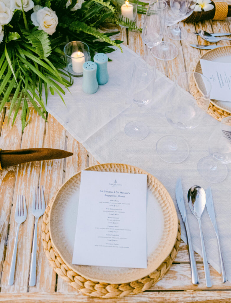 Elegant wedding table setting with menu card, woven charger, and neutral decor at outdoor reception