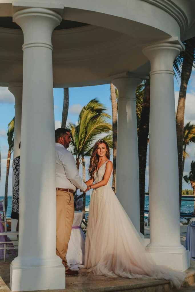 Couple holding hands at tropical ceremony, perfect moment to book a destination wedding by the ocean