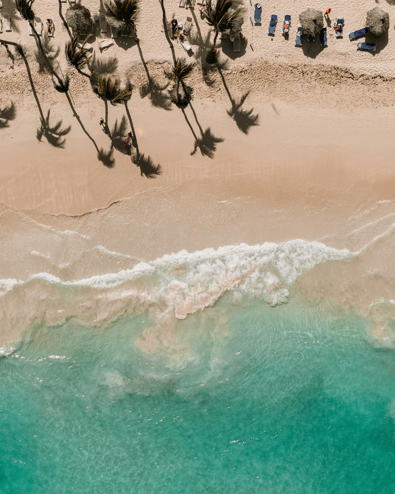 Aerial view of tropical beach and ocean waves, ideal setting to book a destination wedding getaway