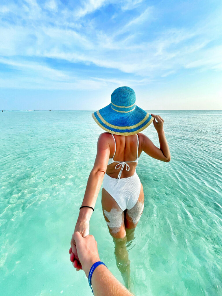 Couple walking through clear ocean water during a romantic honeymoon planned well in advance for relaxation.