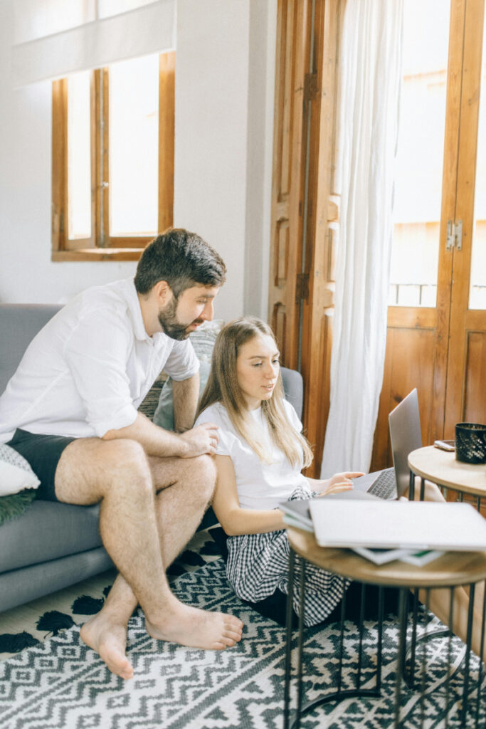 Couple planning travel together at home while deciding how far in advance should you book your honeymoon.