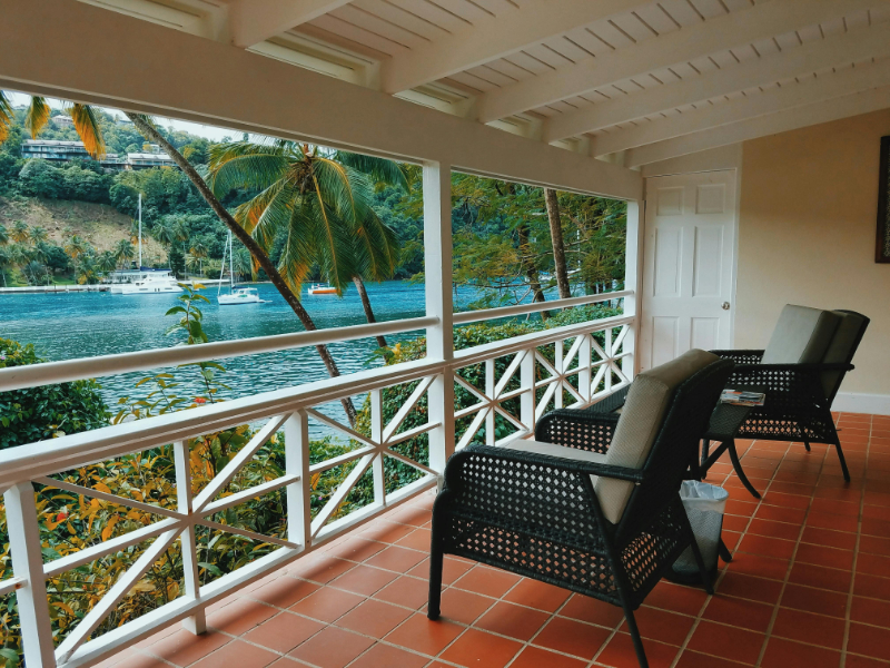 Private honeymoon balcony overlooking tropical water and palm trees at a peaceful luxury resort destination.